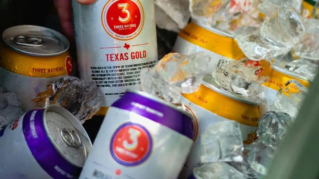 A close-up of beer cans in ice inside a cooler.