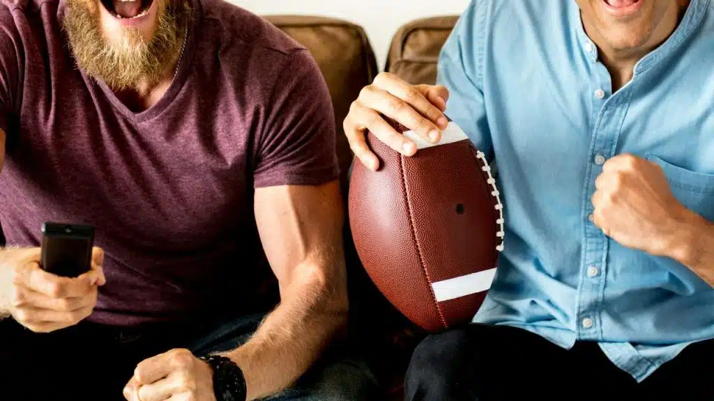 A close-up of two men cheering with a football.