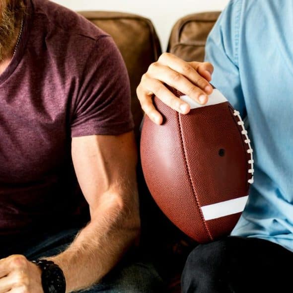 A close-up of two men cheering with a football.