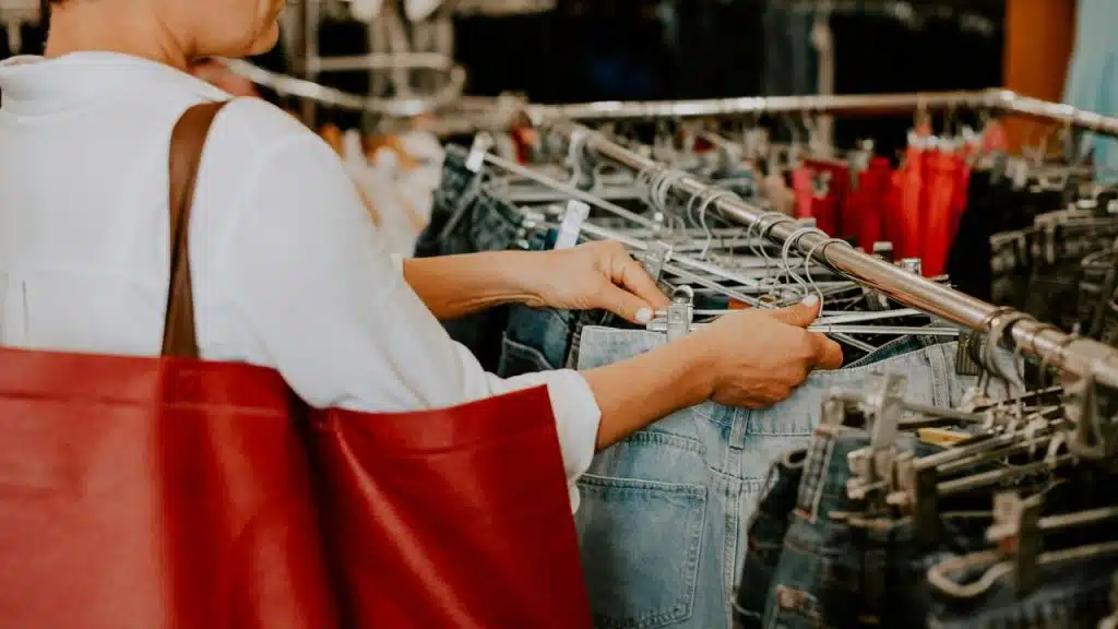 A person shopping for jeans in a clothing store.