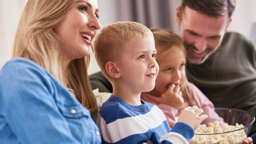 A family sitting together and eating popcorn while watching something.