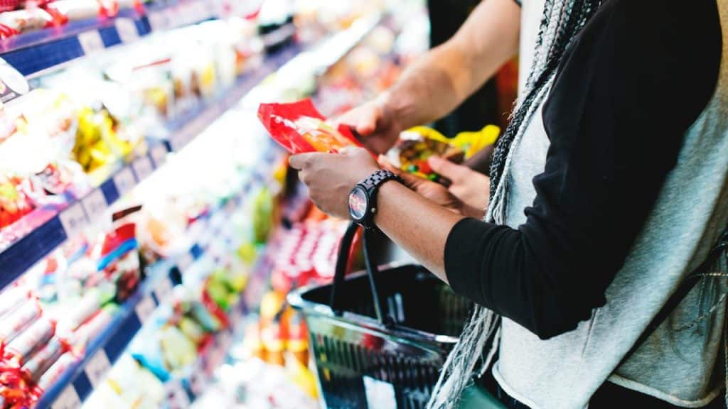 A person shopping for packaged snacks in a grocery store aisle.