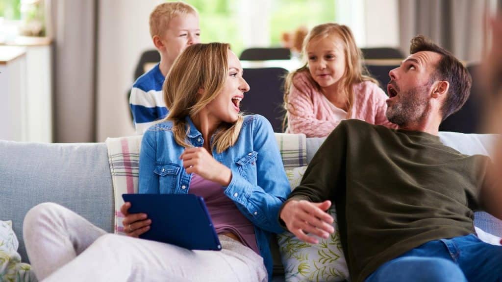 A cheerful family sitting on a couch, laughing and talking together.