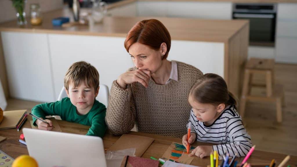 A mother teaching her two children with learning activities at a table.