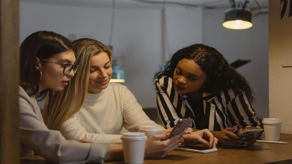 A woman sharing her phone with her friends.