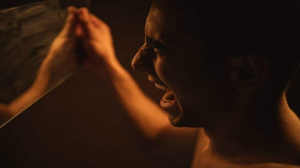 A person crying in front of a mirror.