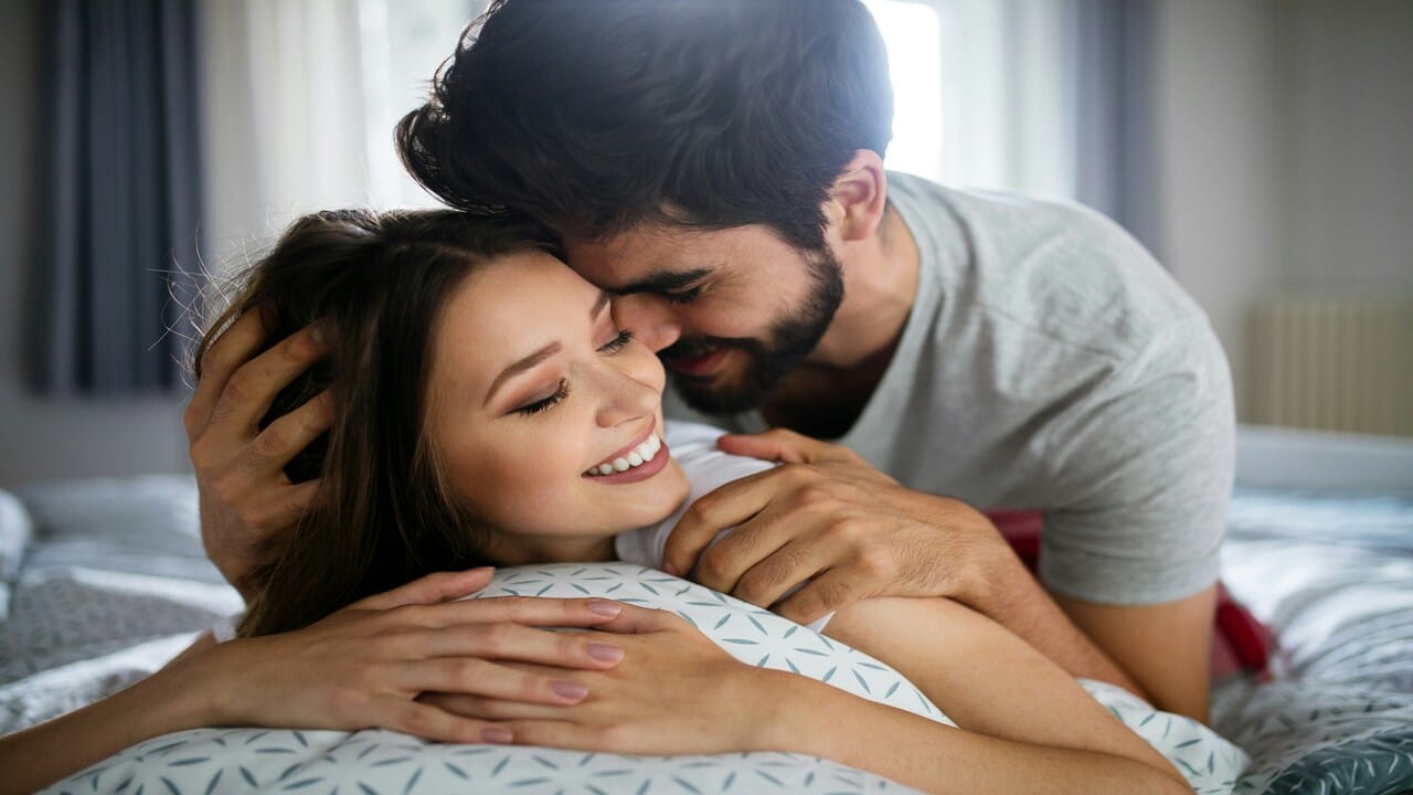 A couple cuddling in bed.