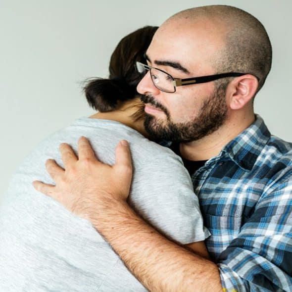 A couple looking sad while hugging
