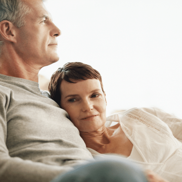 A mature couple sitting on the couch.
