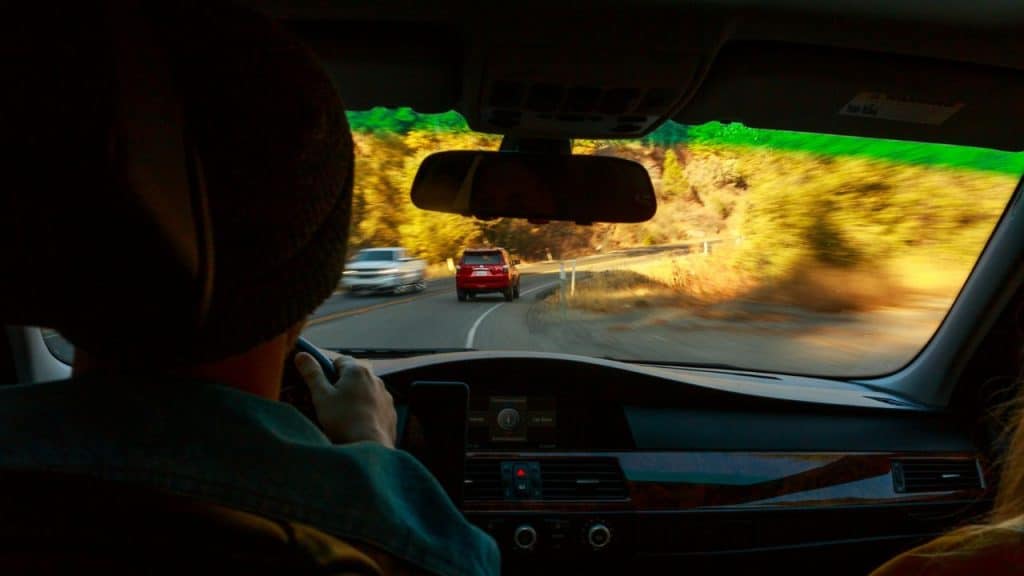 A view from the back of a car, showing the road with other cars in motion.