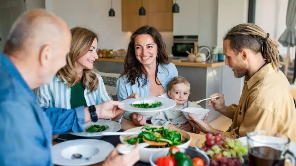 A happy family of adults and a baby sharing a meal together at a table.