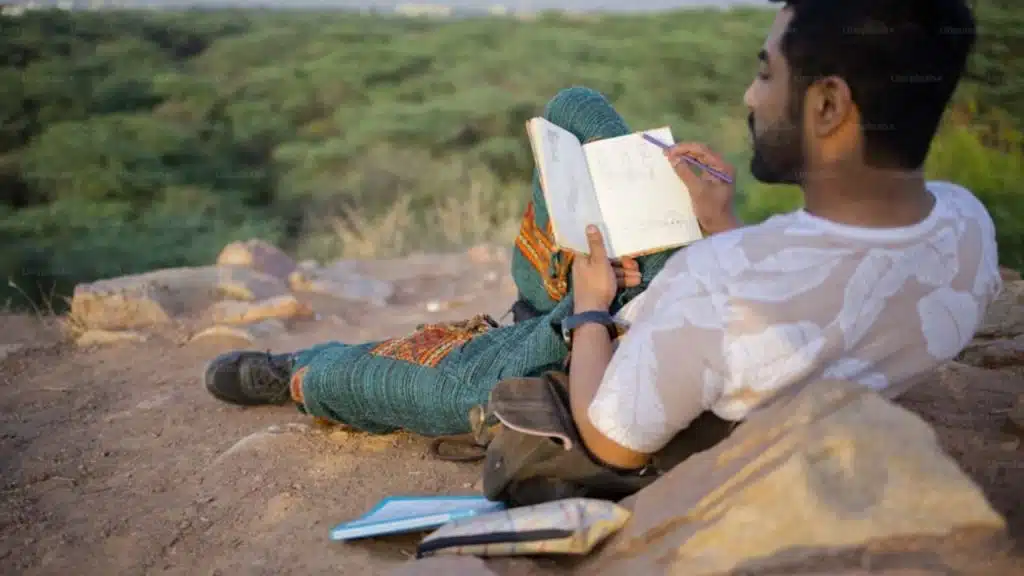 Man journaling or reflecting alone in a peaceful setting.