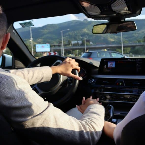 A couple holding hands in the car.