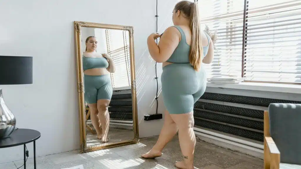 A woman looking sadly at the mirror.