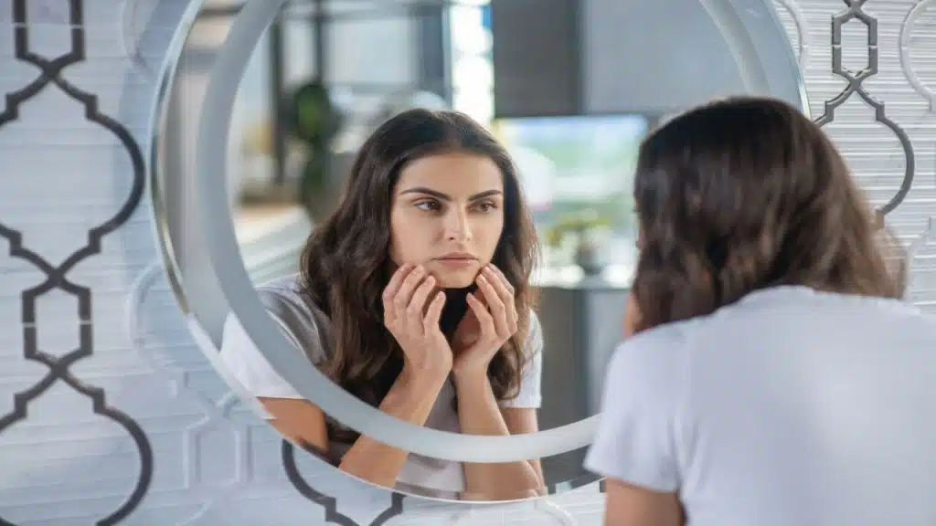 A woman looking at her reflection in the mirror.