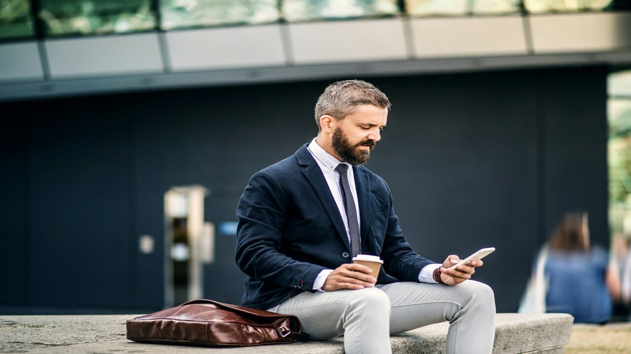 An office worker alone and looking at his phone.