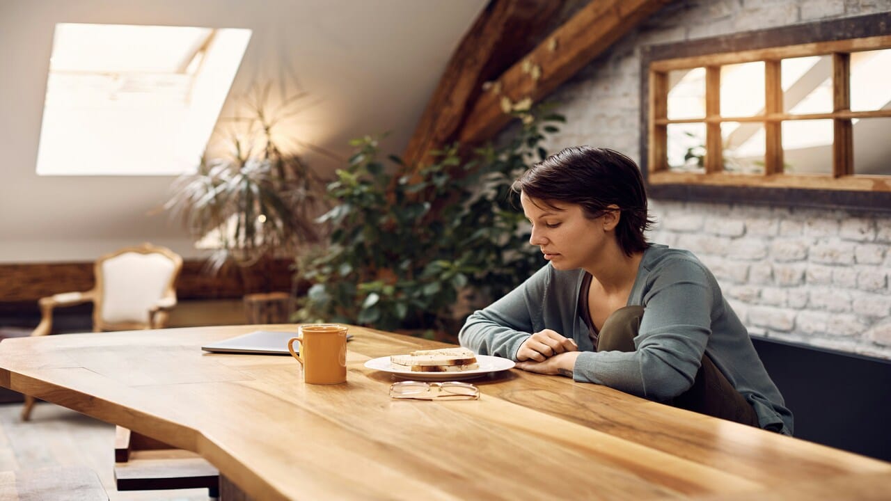 A woman looking sadly at her food.