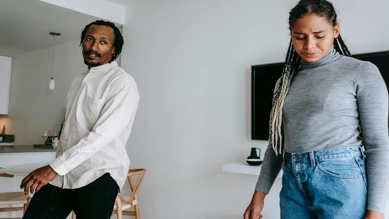 A couple looking sad while in the living room.