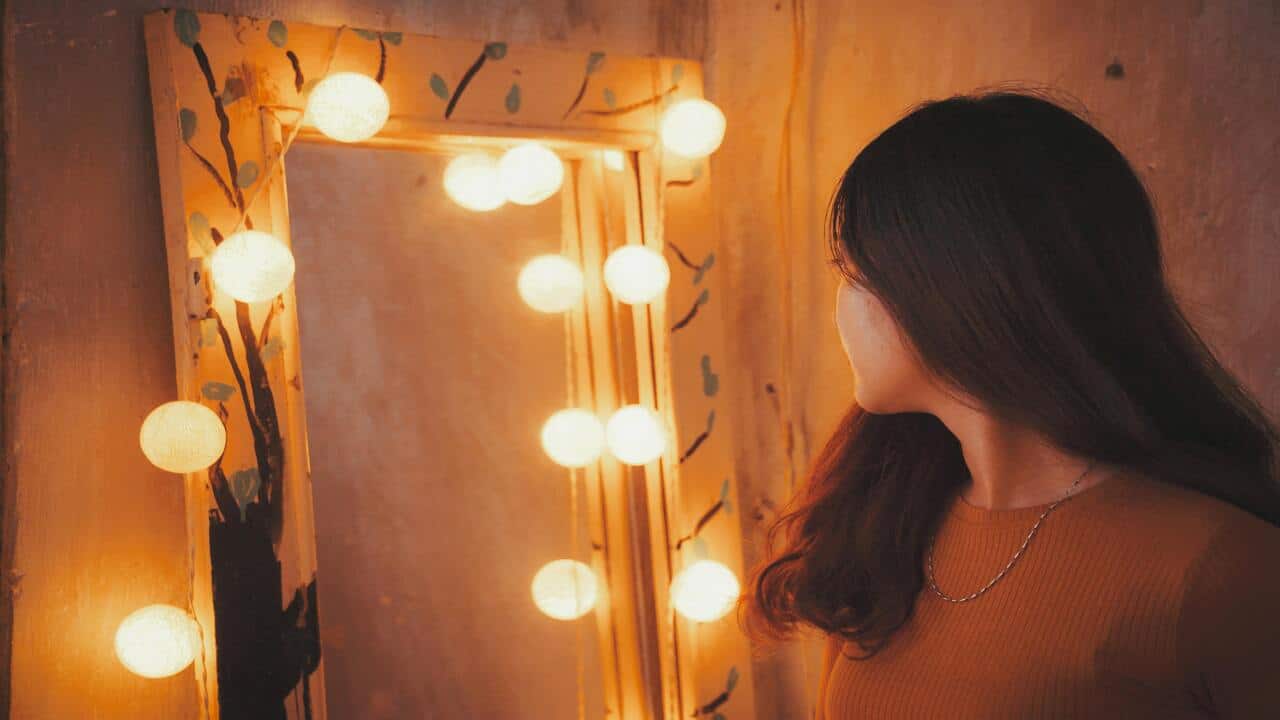 A woman looking sadly at the mirror.
