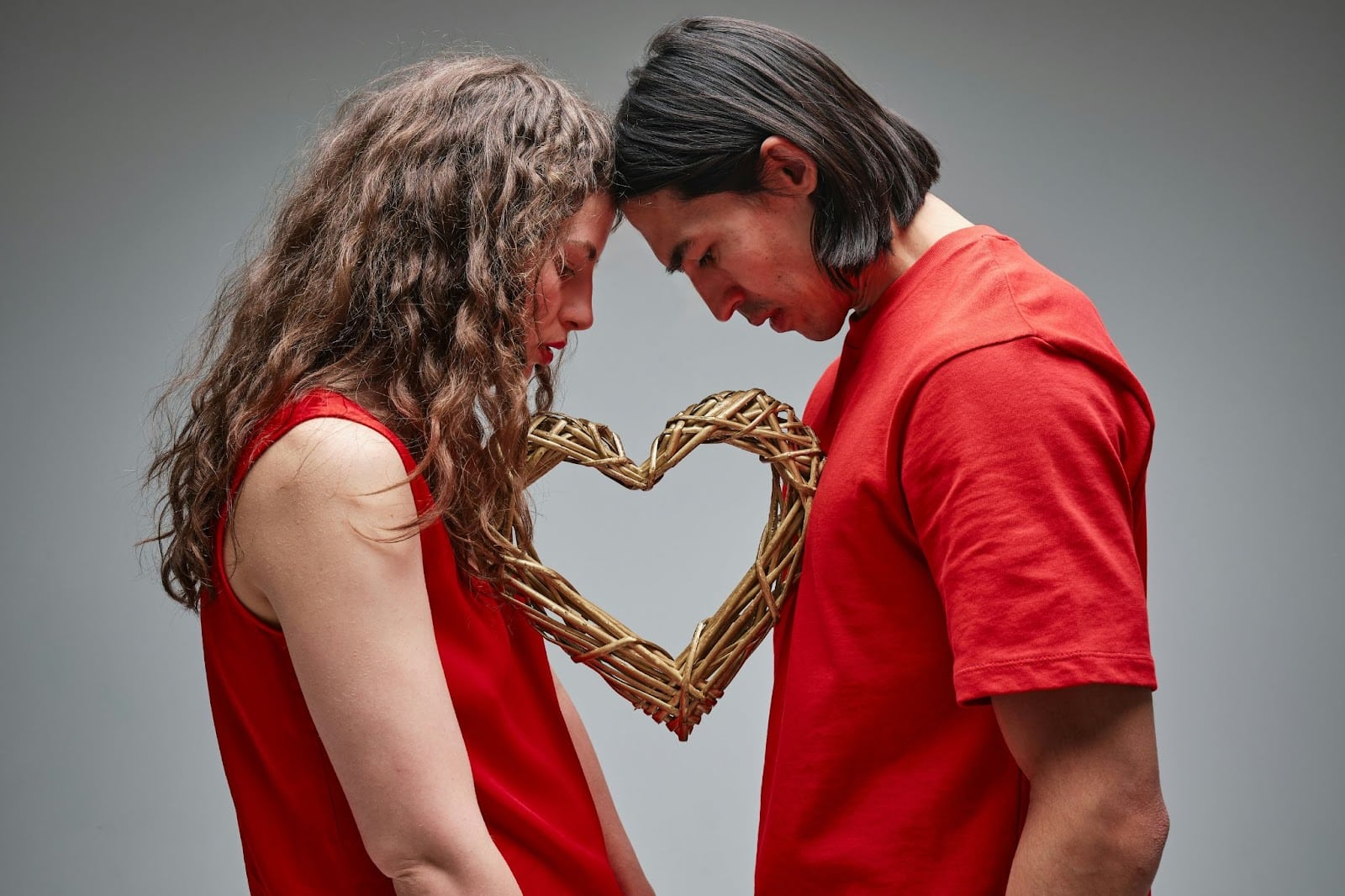 A couple facing each other with heart between them.