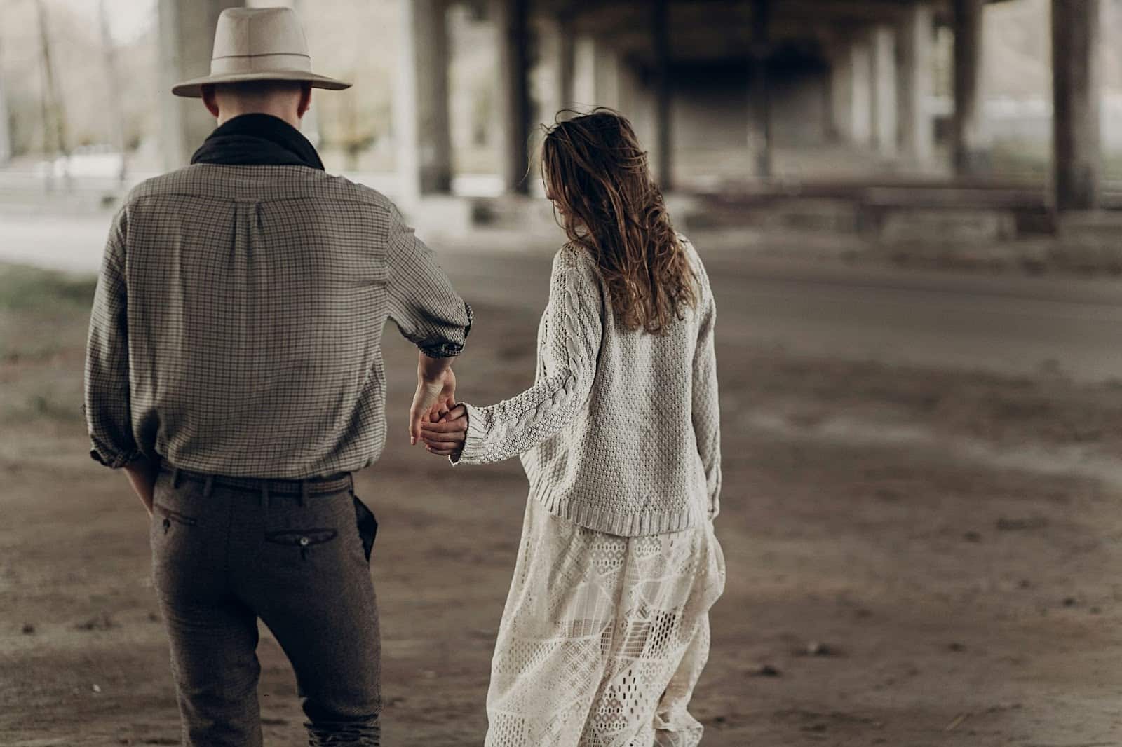 A man and woman walking while holding hands.
