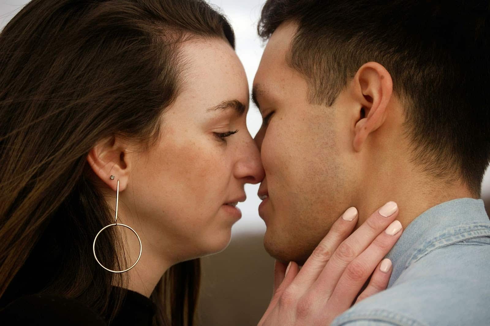 A woman touching a neck of a man.