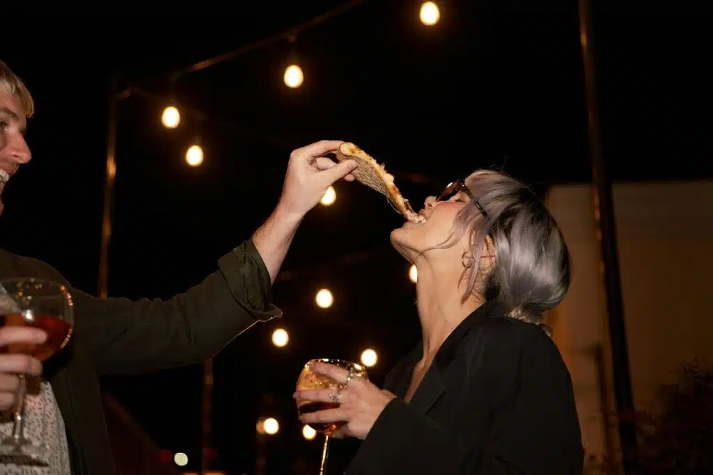 A man letting a woman biting a pizza.