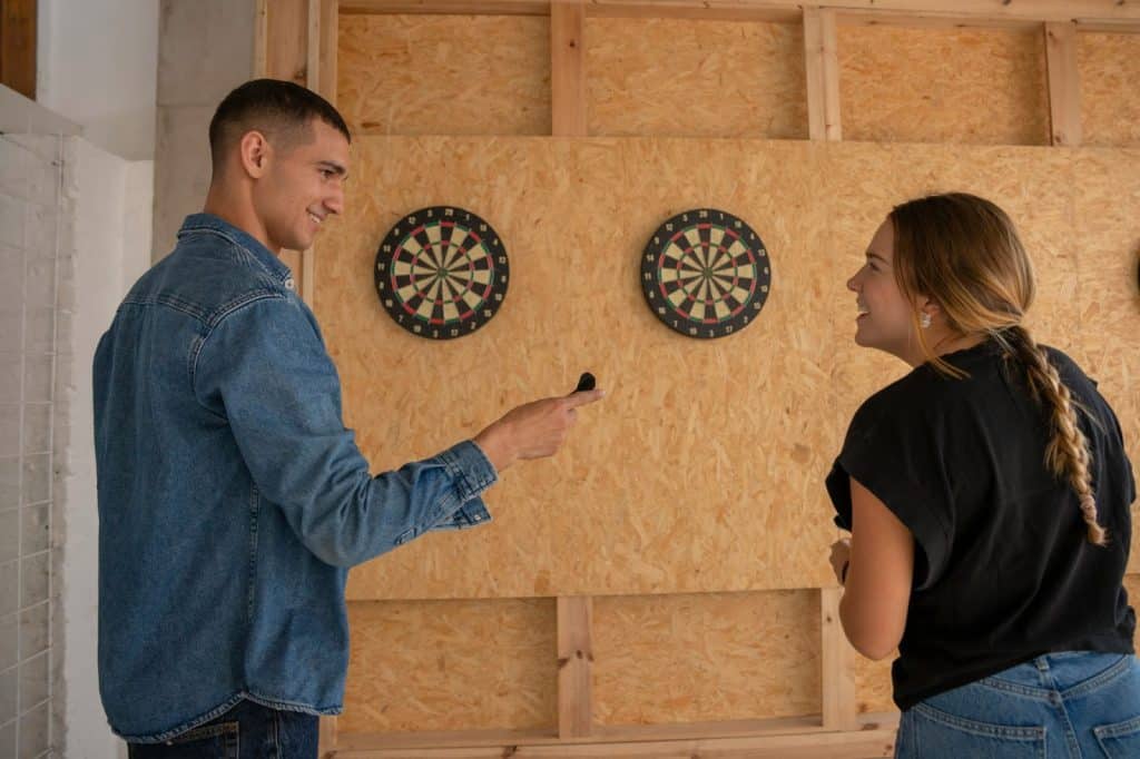 A man and woman playing darts.