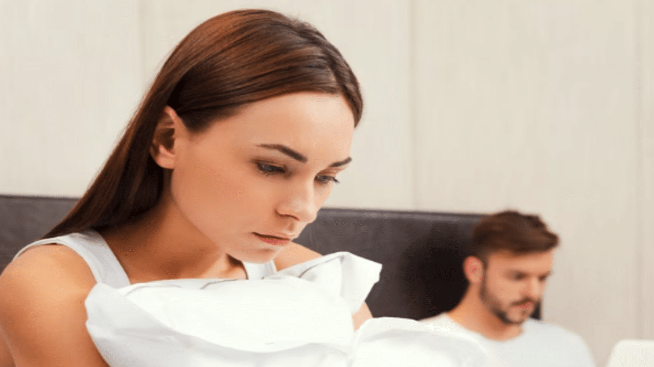 A woman. looking sad with her husband behind her