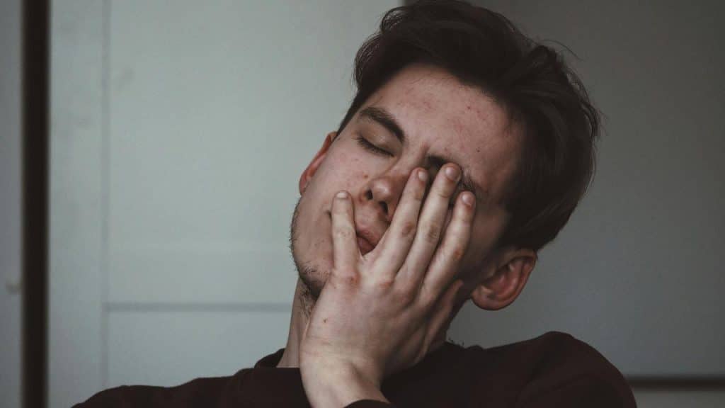 A man with his eyes closed resting his face on his hand.