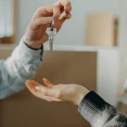 A person handing over a house key to another person.