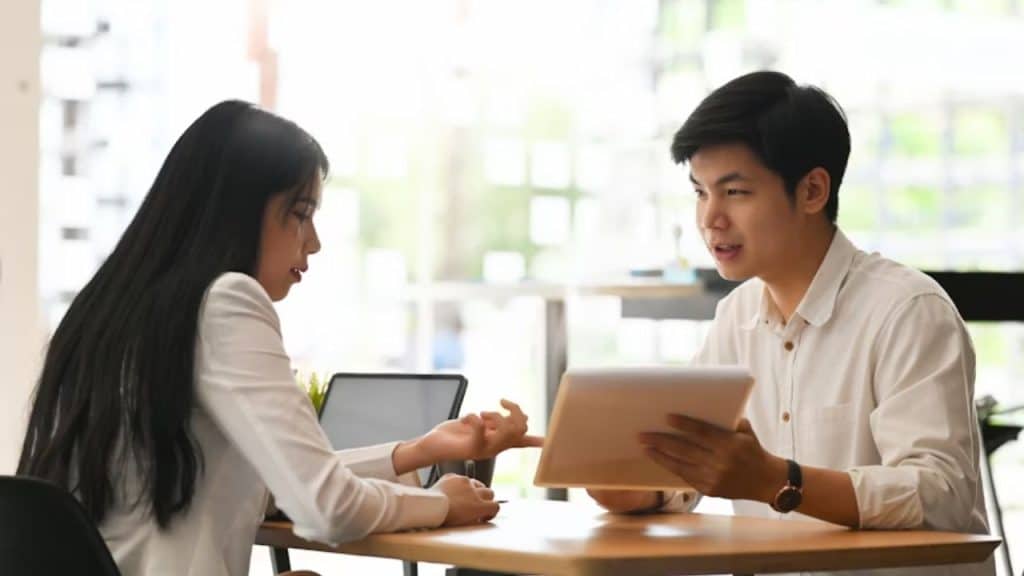 A young couple seated at an outdoor cafe with a bill between them