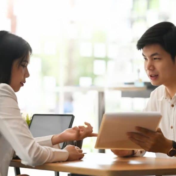 A young couple seated at an outdoor cafe with a bill between them