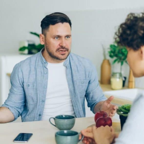 Man shrugging while woman looks frustrated in a home setting