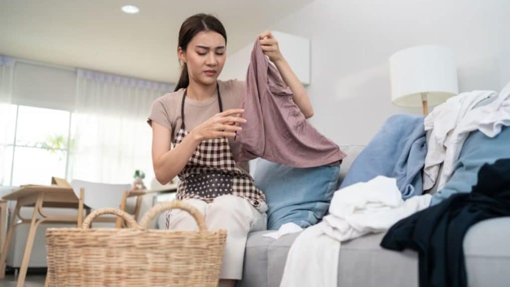 Woman folding laundry with tired expression.