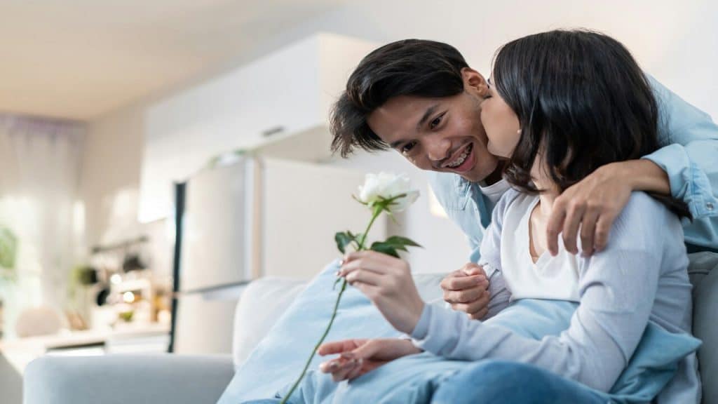 A man apologizing to his wife with a rose.