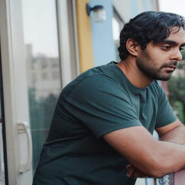 A man looking sad while looking out the balcony.