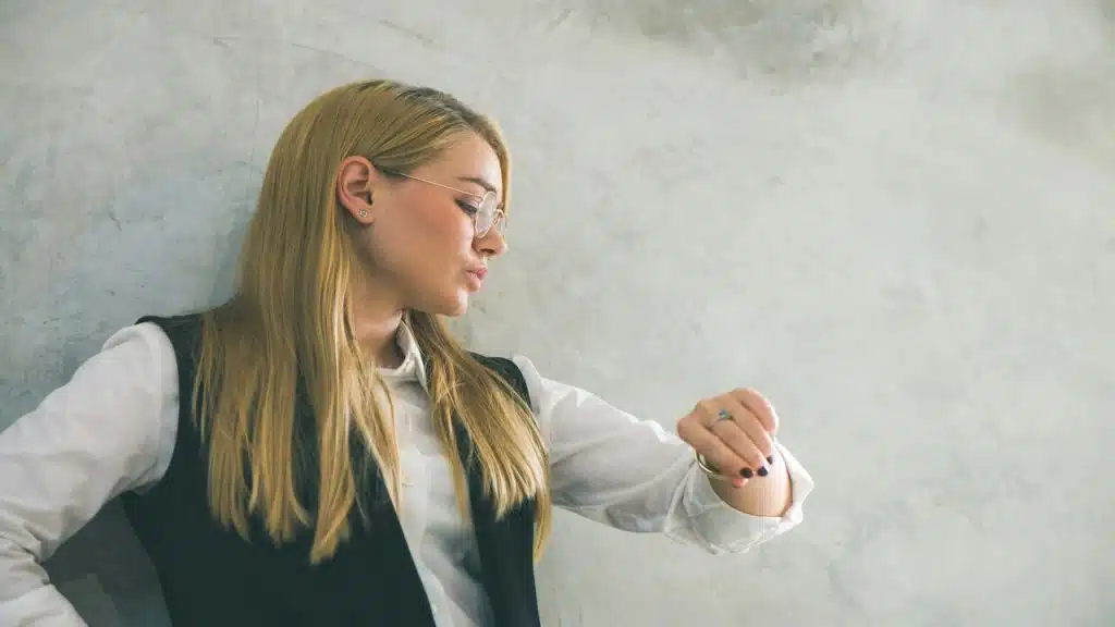 A woman waiting while looking at the time.