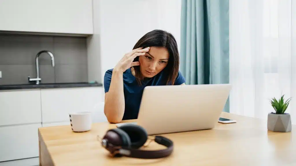 A woman looking at her laptop confused.