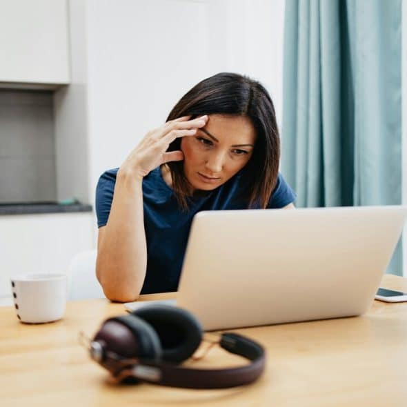 A woman looking at her laptop confused.