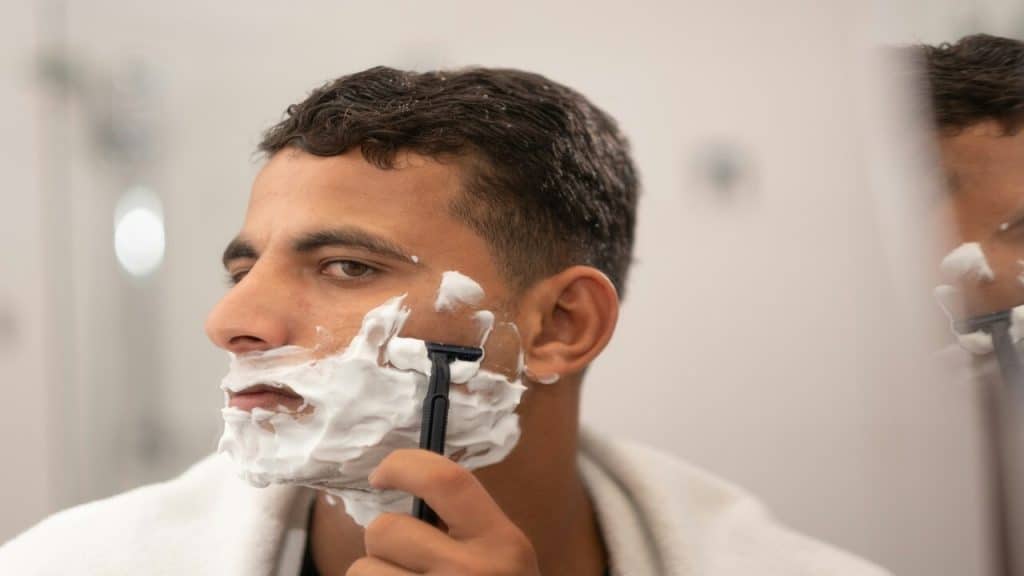 A man shaving in front of the mirror.