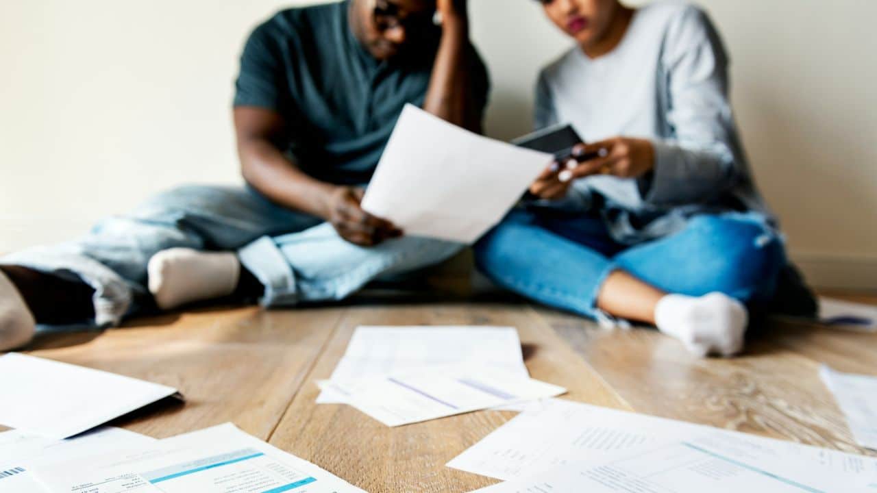 A blurry image shows a man and woman sitting on the floor, looking at papers.
