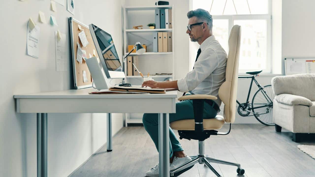 A well-dressed man is sitting at a desk and working on a computer.