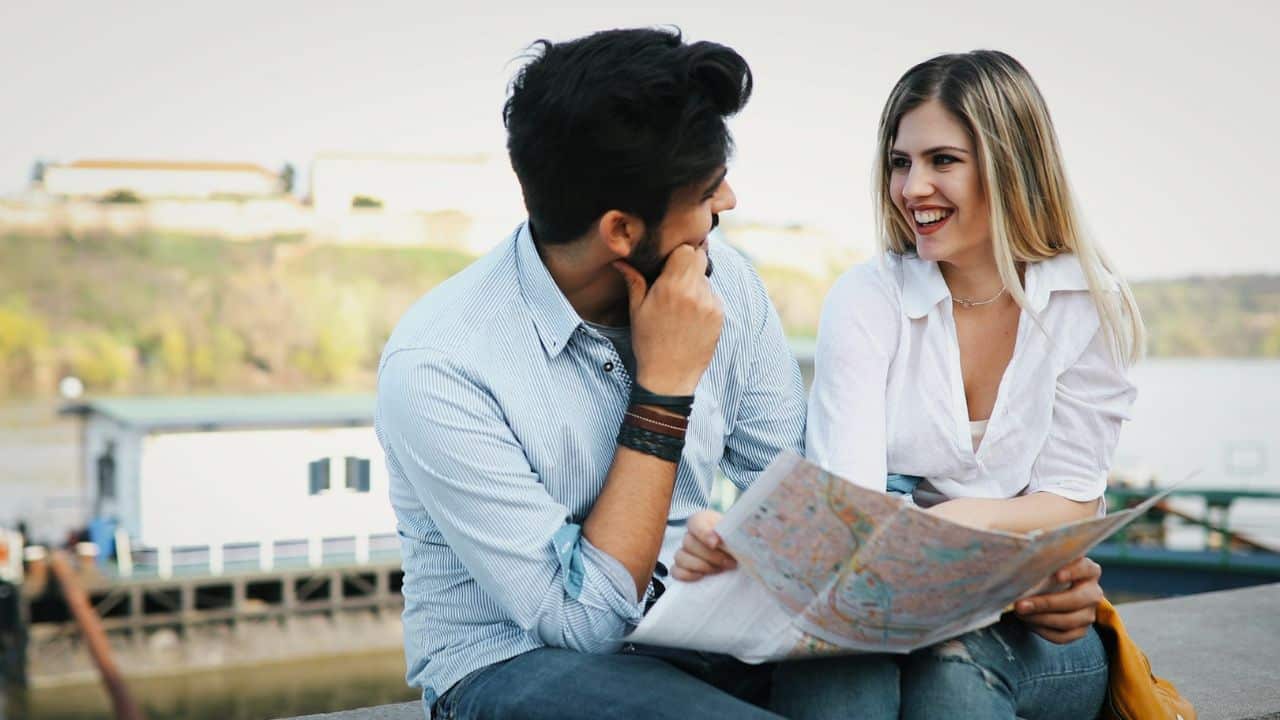 A happy man and woman sit outside, looking at a map.