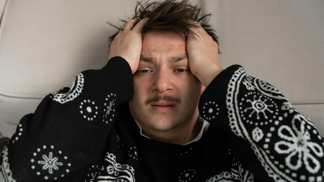 A distressed man is holding his head with both hands.