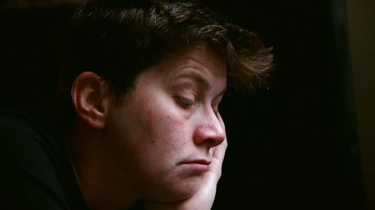 A person with their head resting on their hand in a close-up profile.