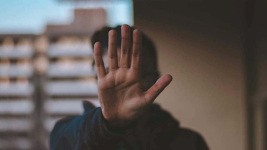 A person holding his hand with the palm outwards towards the camera. 