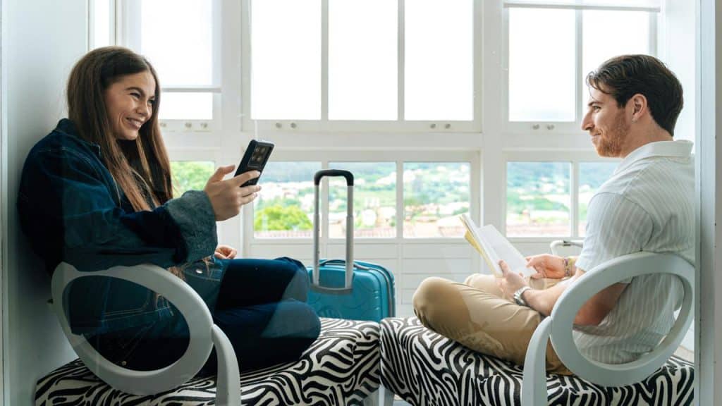 A woman and man sitting by a window, smiling and talking.