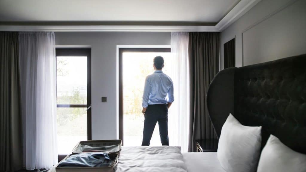 A man standing by a hotel window looking outside.