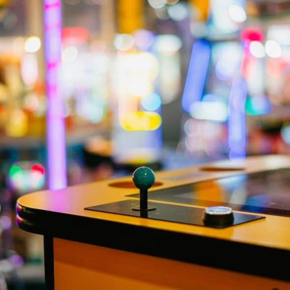 A close-up of an arcade game joystick with colorful lights in the background.